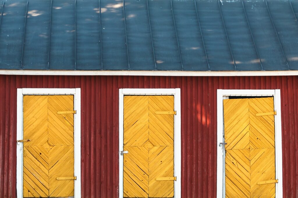 Three vintage yellow doors in a red wooden house with blue roof. Scandinavian design.