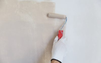 painter hand in white glove painting a wall with paint roller